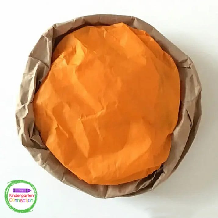 Ball up a piece of orange tissue paper and glue the tissue paper "filling" into the paper bag "crust."
