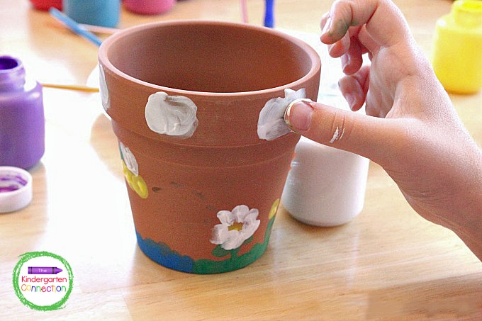 Begin by creating summertime scenes on the sides of the flower pots using only the kids' thumb prints.