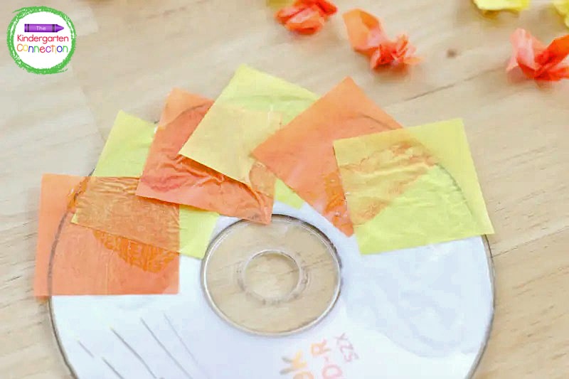 Glue flat pieces of tissue paper onto the CD by overlapping them and creating the "sun rays."