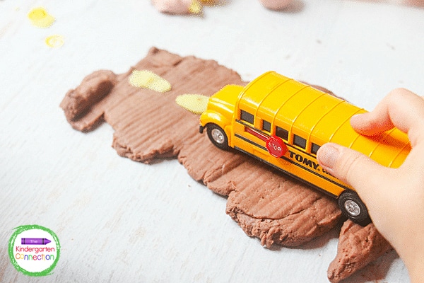 Then they drove the toy bus on the play dough road that they made.