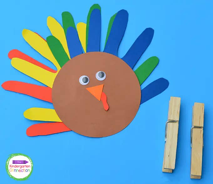 We then glued the handprint feathers to the back of the brown circle, and glued the beak and gobbler/wattle to the front.