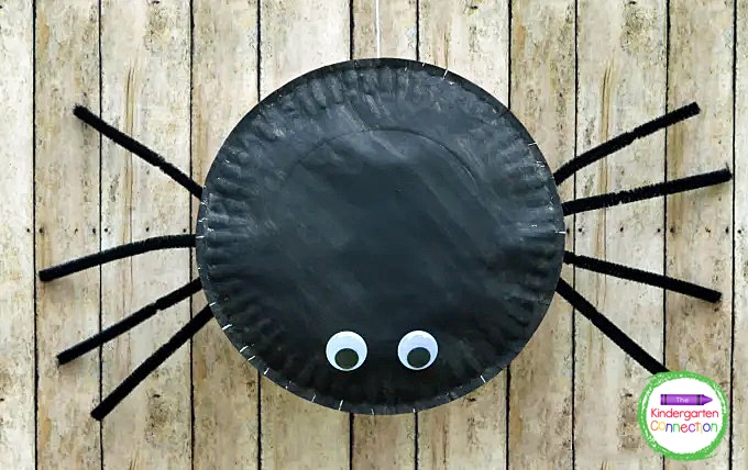 Paint the plate black, attach the pipe cleaners with glue to be the legs, and glue on the googly eyes.
