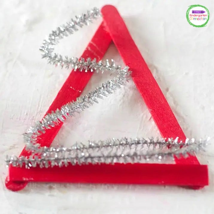 Next, grab the silver pipe cleaner and bend it back and forth, zig-zagging across the popsicle triangles.