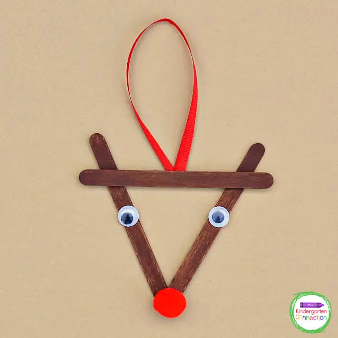 Glue two googly eyes to either side of the craft sticks and a red pom pom as the nose forming the reindeer's face.