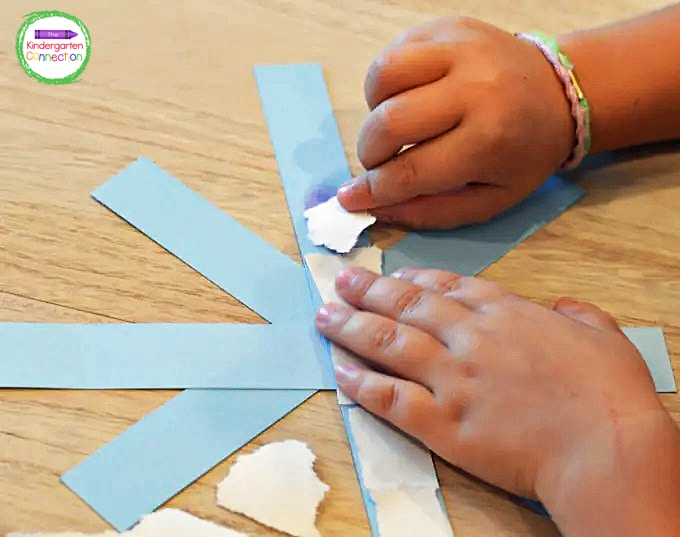 Once they have formed the base of their snowflake, they can begin to tear the white construction paper into smaller pieces.