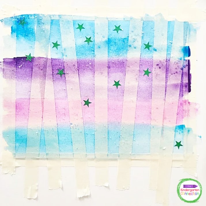 Invite students to use masking tape across the watercolor paper, add star stickers, and watercolor over the top.