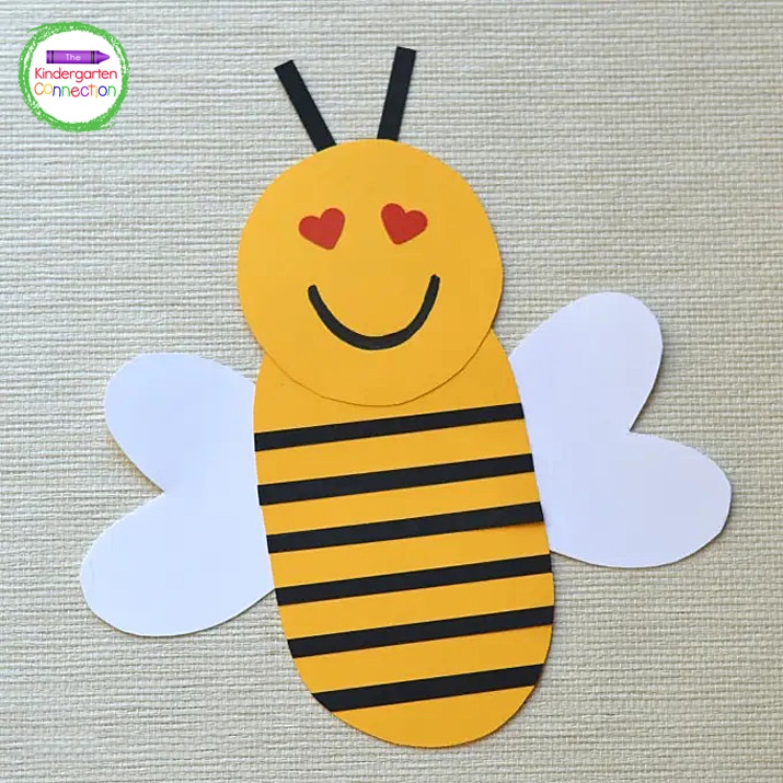 Use the black marker to draw a mouth on the bee and attach two strips of black paper for the antenna.