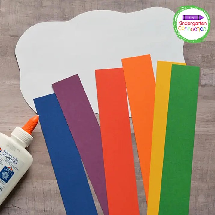 To begin, cut a white cloud from cardstock and different color strips from construction paper.