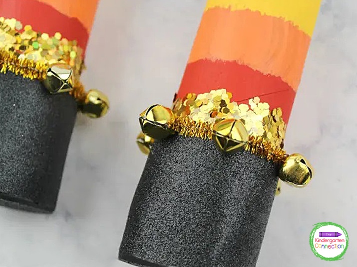 String gold bells onto a gold pipe cleaner and wrap the pipe cleaner around the tube.