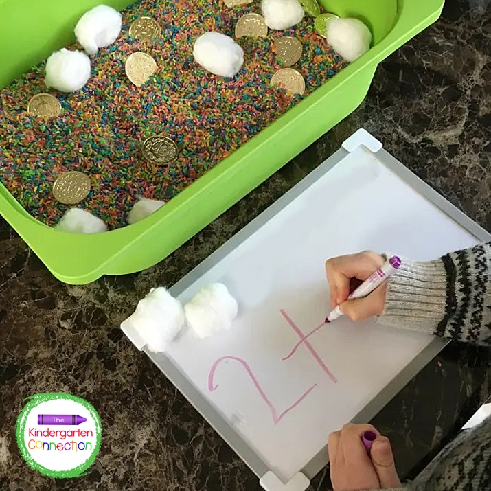 Students roll the dice, write that number on their whiteboard, and remove that number of cotton balls from the bin.
