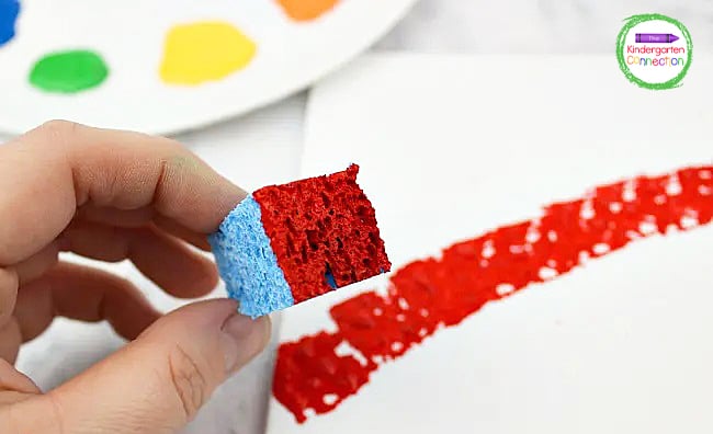 Dab a sponge into the paint and stamp it onto the canvas to start creating the shape of a traditional rainbow.