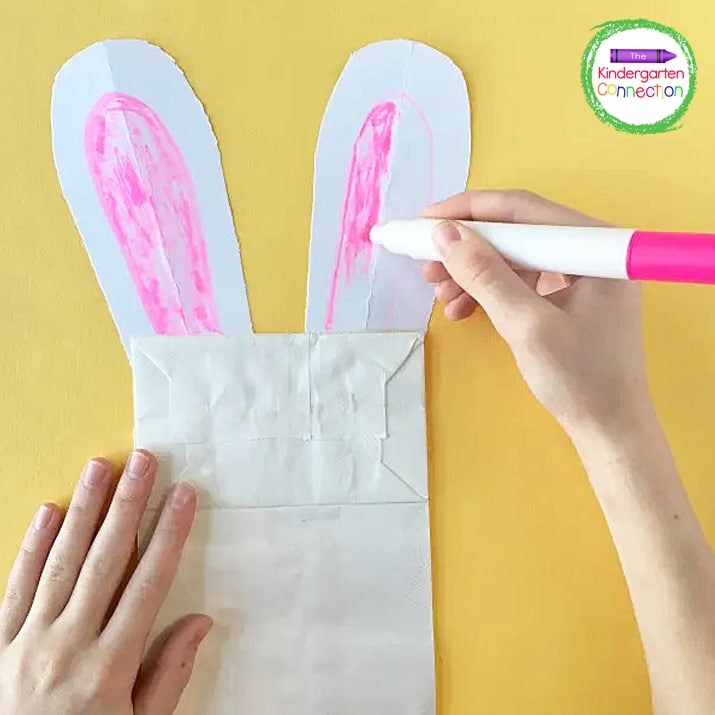 Invite the students to attach the rabbit's ears to the paper bag with glue or tape.