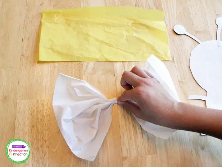 Lay the tissue paper flat and then pinch it in the middle to create a wing.