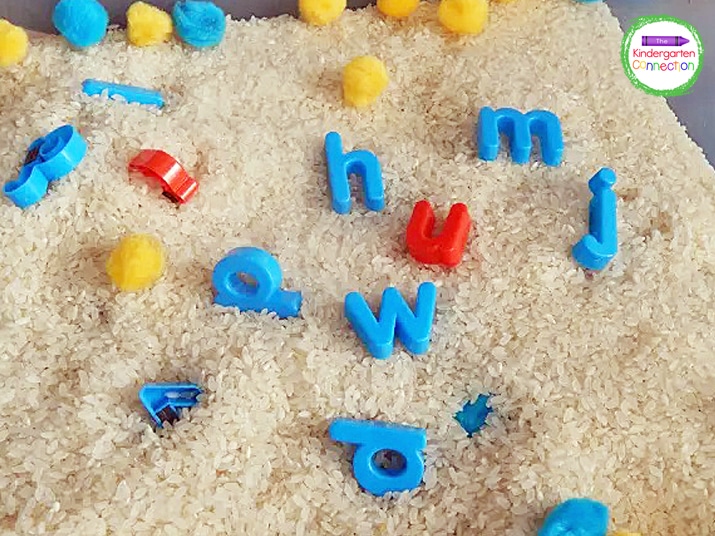 Adding pom poms and letter magnets to a sensory bin adds a hands-on element to learning the alphabet.