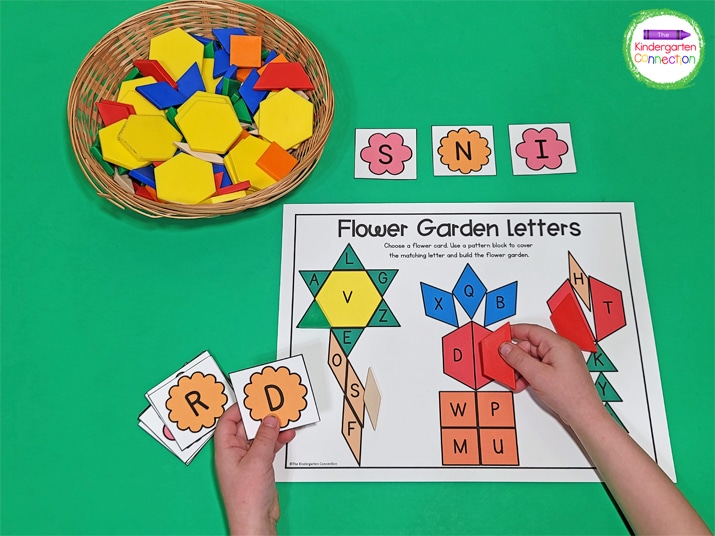 Students choose a flower card and cover the matching letter with a pattern block to build the flower garden.